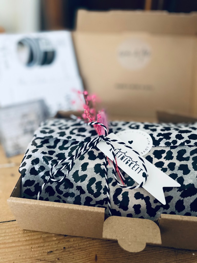 Verpackung handgemachter Keramik mit Seidenpapier im Leo-Look. Liebevoll arrangierte Versandvorbereitung im Atelier, Kombination aus natürlichem Ton und modernem Muster. Detailaufnahme einer besonderen Geschenkverpackung für handgefertigte Keramikstücke aus einer kleinen Manufaktur.