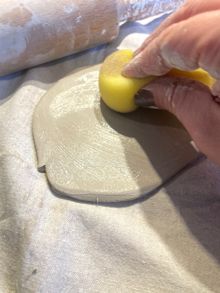 Töpferarbeit im Atelier: Hände formen weichen Ton auf dem Arbeitstisch. Schritt im handwerklichen Herstellungsprozess von Keramik, ruhige, konzentrierte Arbeit beim Töpfern in einer kleinen Manufaktur.